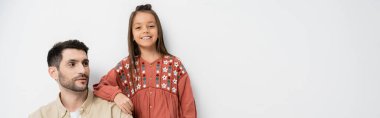 Smiling girl standing near father on white background, banner 