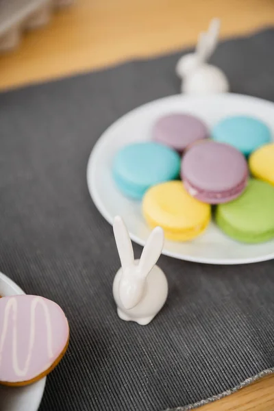 stock image Easter rabbit figurine near colorful macaroons on table at home 