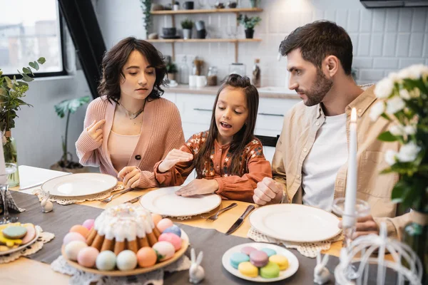 Girl talking near parents during Easter dinner at home