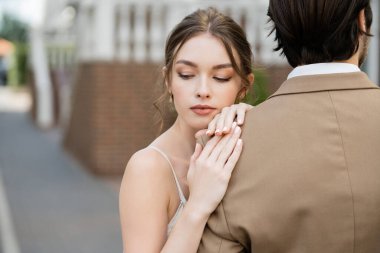 gorgeous bride leaning on shoulder of groom in beige jacket 