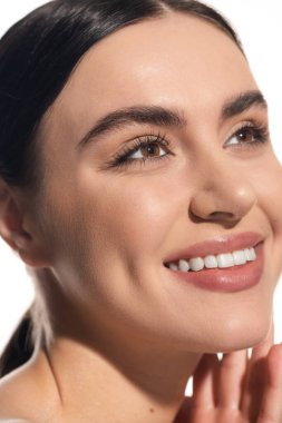 close up of cheerful young woman with natural makeup looking away isolated on white