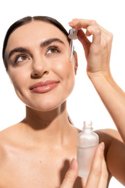 cheerful and brunette woman holding dropped with serum isolated on white 