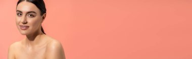 portrait of smiling young woman with bare shoulders and flawless makeup isolated on pink, banner 
