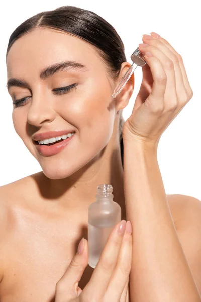 stock image cheerful and brunette woman holding pipette with serum isolated on white 