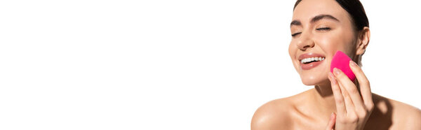 cheerful young woman with natural makeup holding pink beauty sponge isolated on white, banner 