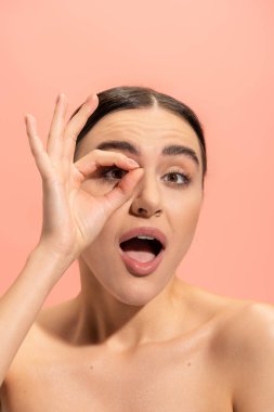 amazed woman with opened mouth showing ok sign isolated on pink 