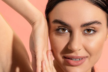 close up view of charming young woman with clenched hands looking at camera isolated on pink 