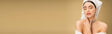 elegant young woman with makeup and luxurious jewelry posing with closed eyes on beige background, banner 