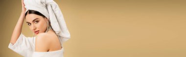 brunette woman with makeup touching white towel on head on beige background, banner 