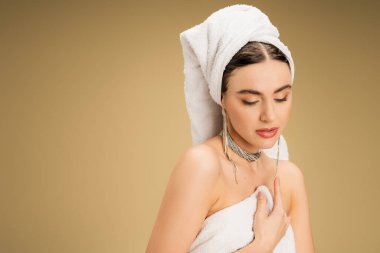 charming young woman in jewelry holding white towel on beige background  clipart