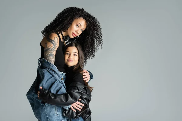stock image Trendy and tattooed woman hugging child isolated on grey 