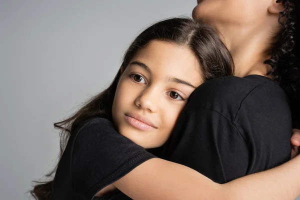 Preteen kid hugging mother in black t-shirt isolated on grey
