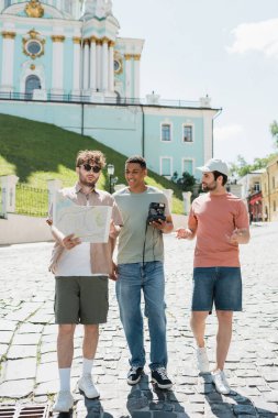 Andrews 'un Kyiv' e inişini gösteren şehir haritasıyla birlikte elinde vintage kamera olan mutlu Afro-Amerikan bir adam.