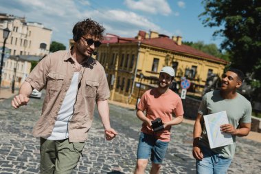Güneş gözlüklü ve kulaklıklı genç tur rehberi neşeli çok kültürlü turistlerle birlikte Kyiv 'e iniyor.