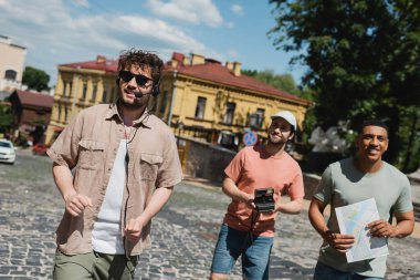 Andrews 'un Kyiv' e inişi sırasında gezi sırasında gülümseyen klasik fotoğraf makinesi ve haritalı pozitif çoklu etnik turistler