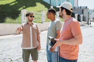 Güneş gözlüklü genç rehber, çok ırklı turistlerin yanında konuşurken Kyiv 'in Podil ilçesini geziyor.