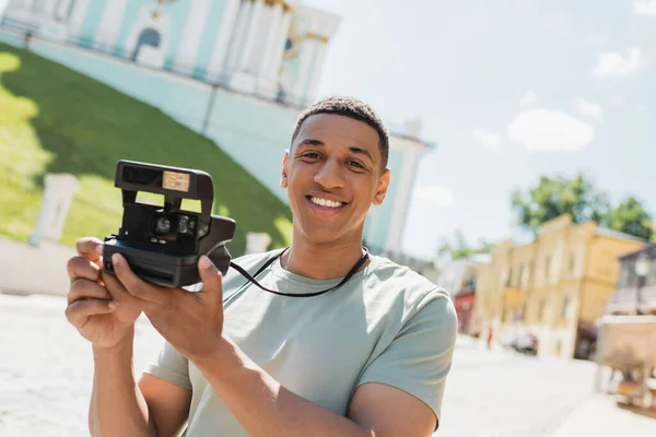 无忧无虑的非洲裔美国游客 带着老式相机微笑着看着安德鲁在基辅的降生 — 图库照片