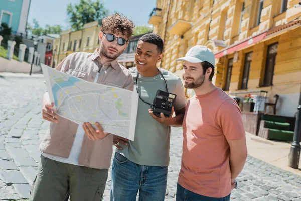 Güneş gözlüklü genç tur rehberi, Kyiv 'in Podil ilçesine yaptığı gezi sırasında gülümseyen çok kültürlü turistlerin şehir haritasını gösteriyor.