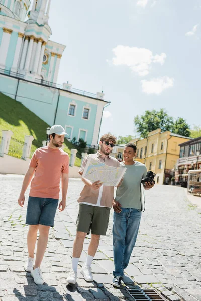 Kyiv 'de Andrews' in şehir haritasıyla tur rehberinin yanında yürüyen çok kültürlü turistlerin tam uzunluğu