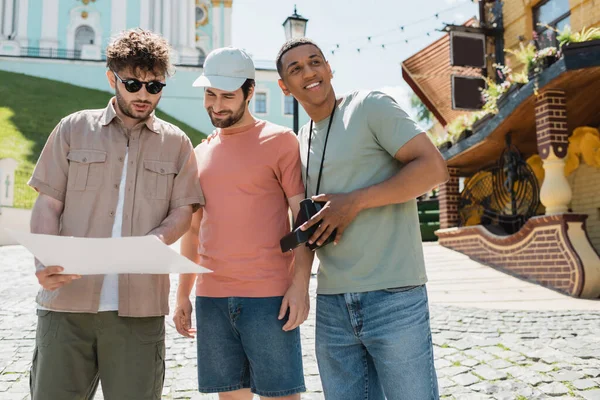stock image young tour guide showing city map to multiethnic travelers on Andrews descent in Kyiv