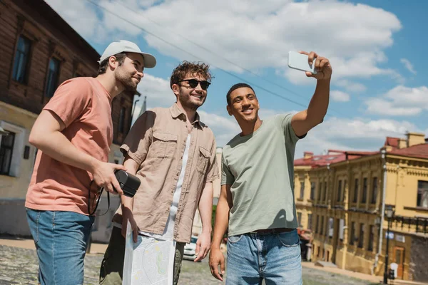 快乐的非洲裔美国旅行者在基辅用智能手机与众多种族的安德鲁后裔男子拍照 — 图库照片