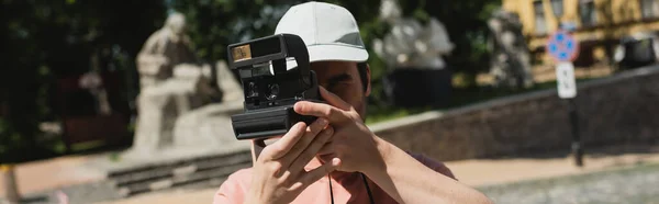 身穿太阳帽的年轻游客在基辅安德鲁下降的老式相机上拍照 — 图库照片