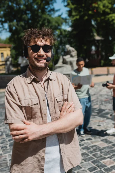 年轻快乐的导游戴着太阳镜和耳机 手挽手站在基辅安德鲁斯瀑布上 — 图库照片