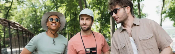 기사보기 선글라스를 가이드가 공원에서 모자를 현수막을 관광객들 이야기를 나누고 — 스톡 사진