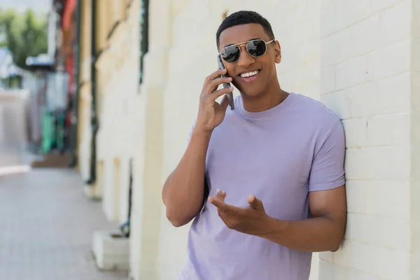 Sonriente Hombre Afroamericano Gafas Sol Hablando Por Teléfono Móvil Calle — Foto de Stock