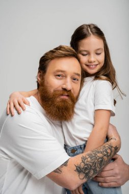 Sakallı adam kaygısız kızı kucaklıyor. Gri yolda izole edilmiş. 