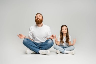 Gülümseyen adam ve kızı gri arka plan üzerinde meditasyon yaparken Gyan Mudra yapıyor.