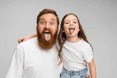 Genç bir çocuk ve sakallı bir baba. Gri üzerine izole edilmiş diller uzatıyorlar.  