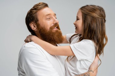 Sakallı adam, neşeli çocukluk çocuğunu kucaklıyor. Gri yolda izole edilmiş.  