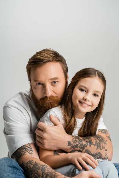 Бородатый Татуированный Отец Обнимает Улыбающуюся Дочь Изолированную Серой — стоковое фото