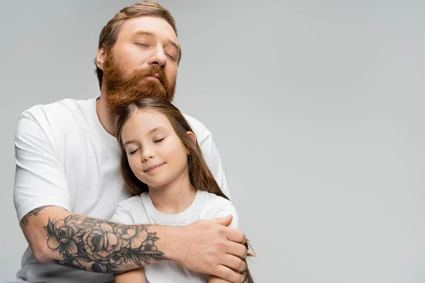 紧闭双眼的纹身男子 抱着笑着的十几岁前的女儿 与灰蒙蒙隔离 — 图库照片