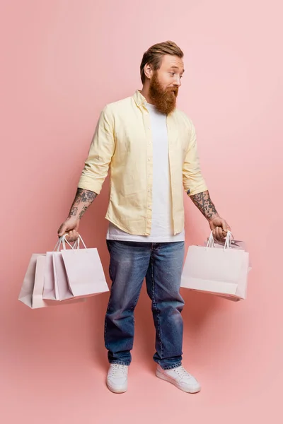 Homem Tatuado Confuso Segurando Sacos Compras Fundo Rosa — Fotografia de Stock