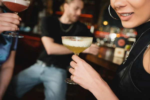 在酒吧与朋友共度时光时 一个微笑的非洲裔美国女人举着泡沫鸡尾酒的照片 — 图库照片
