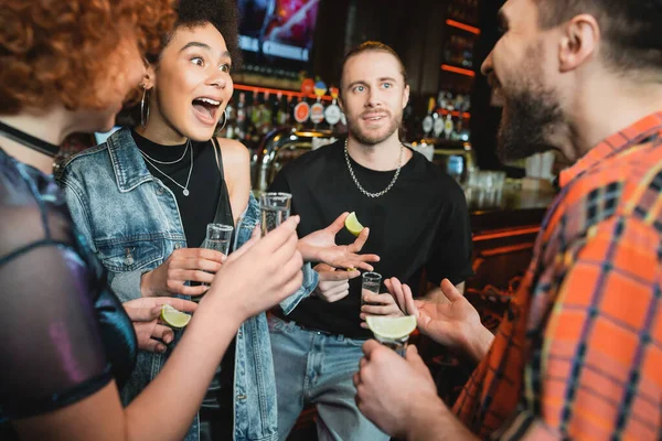 Excitada Afro Americana Segurando Tequila Tiro Perto Amigos Borrados Bar — Fotografia de Stock