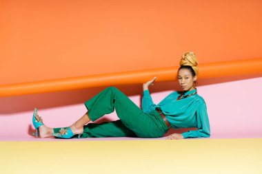 Renkli arka planda poz veren türbanlı modacı Afro-Amerikan modeli 