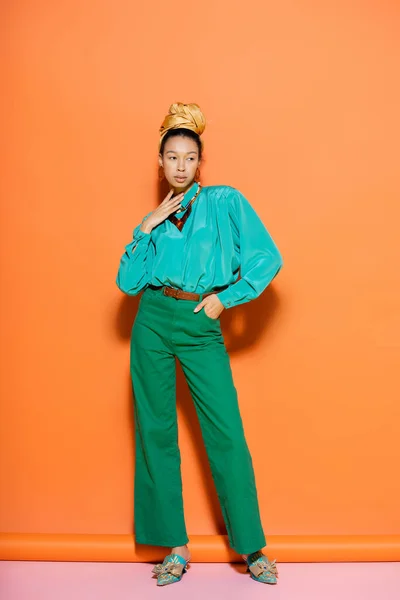 夏の服でファッショナブルなアフリカ系アメリカ人モデルの完全な長さ離れてオレンジとピンクの背景を見ます — ストック写真