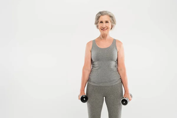 Gri Saçlı Mutlu Yaşlı Kadın Gri Renkli Dambıllarla Egzersiz Yapıyor — Stok fotoğraf