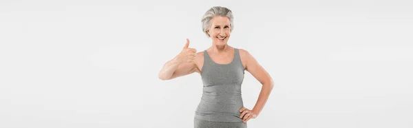 穿着运动服的快乐而退休的女人 手挽着髋关节摆着姿势 在灰色的横幅上显得孤立无援 — 图库照片