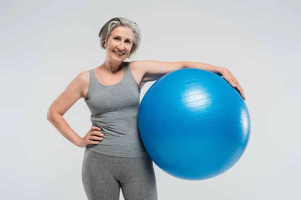 Vrolijke Senior Vrouw Sportkleding Houden Blauwe Fitness Bal Geïsoleerd Grijs — Stockfoto