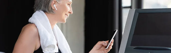 Ευτυχισμένη Ηλικιωμένη Γυναίκα Ασύρματο Ακουστικό Κρατώντας Smartphone Ενώ Στέκεται Κοντά — Φωτογραφία Αρχείου