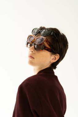 portrait of brunette woman wearing several different sunglasses isolated on grey clipart