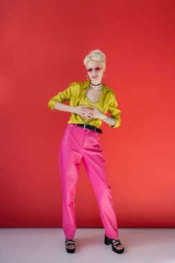 Tam boy mutlu albino modeli. Dövmeli el. Carmine Pembesi üzerinde şık topuklu sandaletler giyiyor. 
