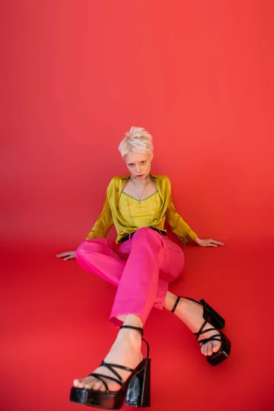 全长的年轻模特 穿着时髦的衣服 脚跟凉鞋 衬托在红宝石粉红的背景上 — 图库照片