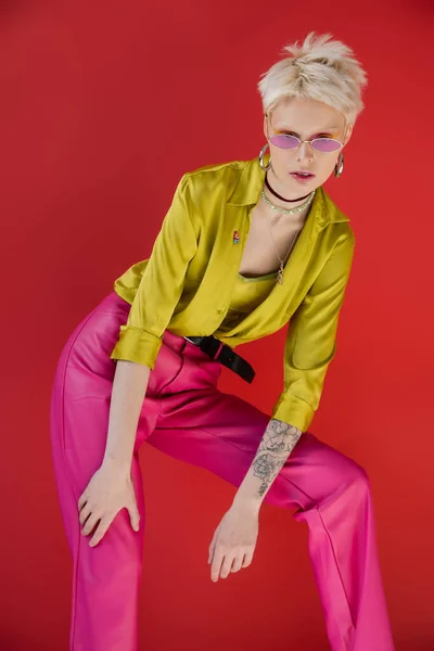stock image albino model with tattooed hand posing in trendy blouse and sunglasses on carmine pink 