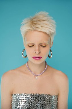 blonde albino woman in shiny top with sequins looking down on blue background  clipart