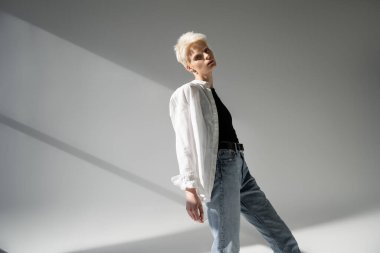 Siyah tişörtlü albino kadın ve gri arka planda gölgeli beyaz gömlek.